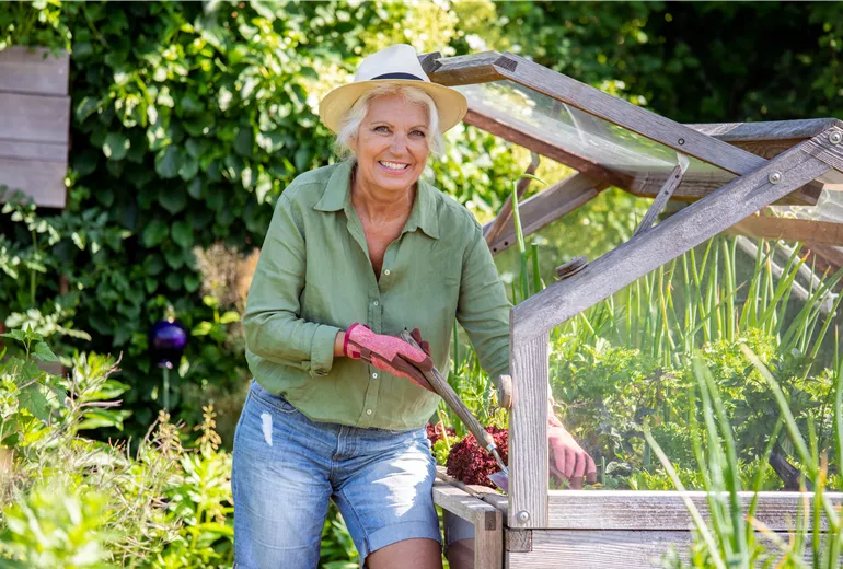 Gartenarbeit - Frau am Hochbeet mit Gartenschaufel